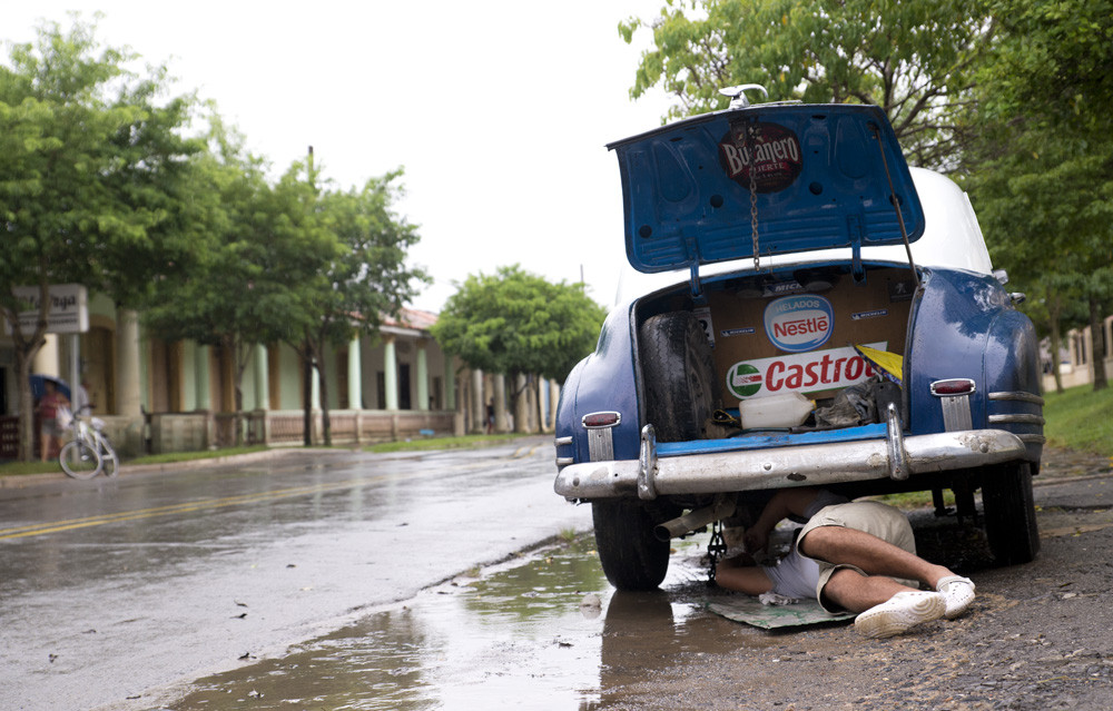 A driver fixing his late 1940's GMC during a downpour in Vinales.